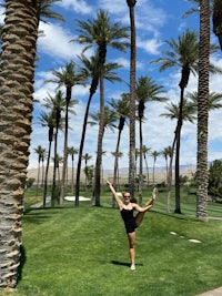a woman doing yoga in front of palm trees