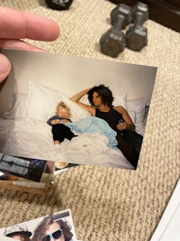 a woman holding a photo of a baby on a bed