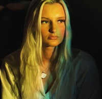 a woman with long blonde hair is sitting in a dark room