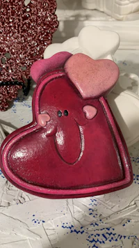 a red heart with a smile on it is sitting on a table