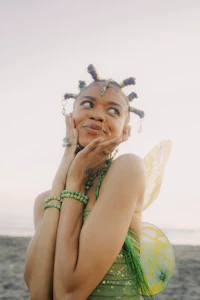 a woman in a green fairy costume posing on the beach