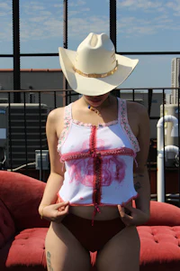 a woman in a cowboy hat sitting on a red couch