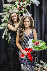 two women are posing for a picture in front of flowers