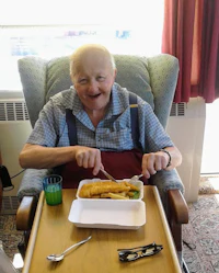 a man sitting in a chair eating a meal