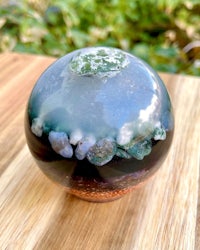 a blue and green glass ball sitting on top of a wooden table