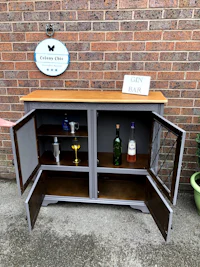 a person is standing next to a wooden bar cabinet