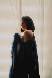 a woman in a blue dress posing in front of a curtain