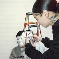a woman taking a picture of a man with a mask
