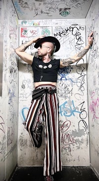 a man wearing a hat and striped pants in an elevator