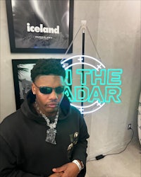a man in sunglasses standing in front of a neon sign