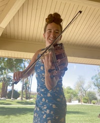 a woman in a blue dress holding a violin