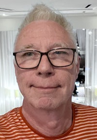 a man wearing glasses and an orange striped shirt