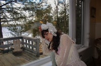 a woman in a white dress leaning against a window