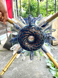 a person is holding up a blue and gold sculpture
