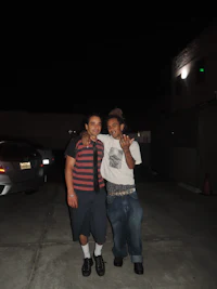 two men standing next to each other in a parking lot