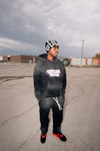a man in a black hoodie standing in a parking lot