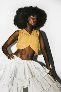 a black woman in a yellow top and white skirt
