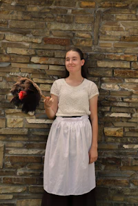 a girl in a white apron holding a hat