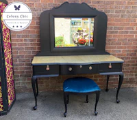 a black dressing table with a mirror and stool