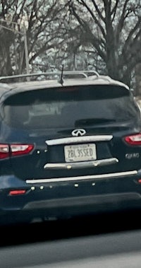 a black infiniti suv driving down the road