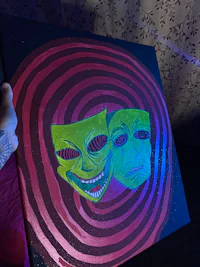 a person is holding a painting with two faces on it