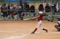 a softball player swings at a ball during a game