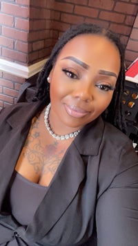 a woman with tattoos and a blazer posing for a photo