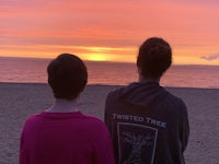 two women looking at the sunset on the beach
