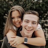a man and woman hugging in front of a tree