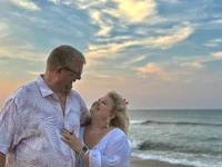 a couple standing on the beach at sunset