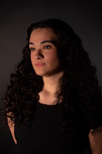 a woman with long curly hair is posing for a photo