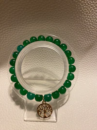 a green beaded bracelet on a white surface