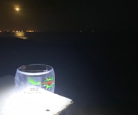 a solar powered cup sitting on a table next to the ocean
