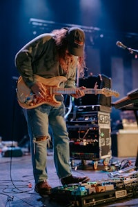 a man with long hair playing a guitar on stage