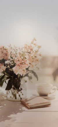 a vase of flowers on a table with a cup of coffee