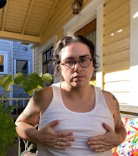 a woman wearing glasses and a tank top standing on a porch