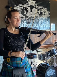 a woman in a kilt playing the violin