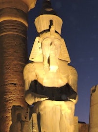 a statue of an egyptian pharaoh lit up at night