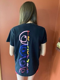 the back of a woman wearing a black t - shirt with a rainbow design on it