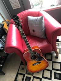 an acoustic guitar sitting on a red chair