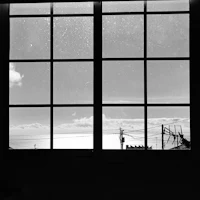 a black and white photo of a window with a view of the ocean