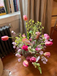a vase of flowers sitting on a wooden floor