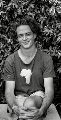 a black and white photo of a young man sitting on a bench