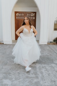 a bride in a wedding dress standing in front of a church