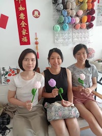 three chinese women sitting on a couch holding flowers