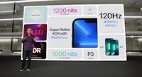 a man standing in front of a large screen showing different types of phones