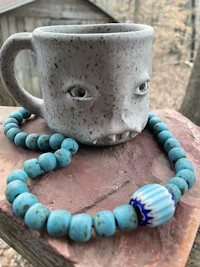 a blue beaded necklace with a mug on it