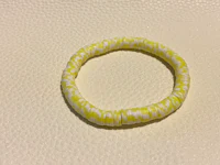 a yellow and white striped bracelet on a white surface