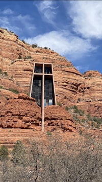 a small building sits on top of a red rock