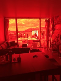 a living room with a red light shining through the window